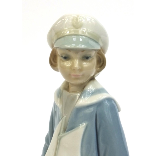 2134 - Lladro figure of a young girl seated holding a model boat, factory marks to the base, 23cm high