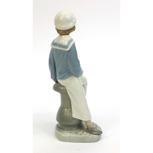 2134 - Lladro figure of a young girl seated holding a model boat, factory marks to the base, 23cm high