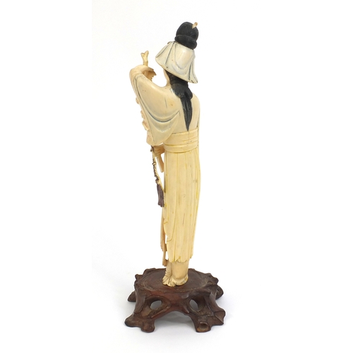 505 - Chinese carved ivory okimono of a girl holding flowers and wearing a robe, raised on a hardwood base... 