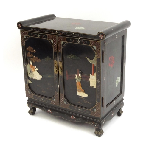 2027 - Oriental black lacquered two door side cabinet  decorated in relief with soap stone, hand painted wi... 