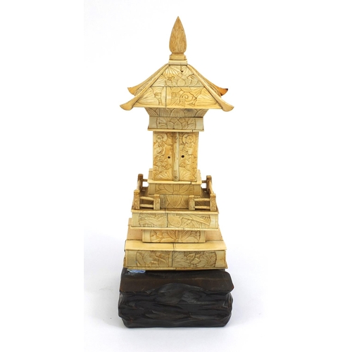 2357 - Oriental ivory pagoda opening to reveal a miniature Buddha, raised on a hardwood base, 26cm high