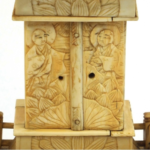 2357 - Oriental ivory pagoda opening to reveal a miniature Buddha, raised on a hardwood base, 26cm high