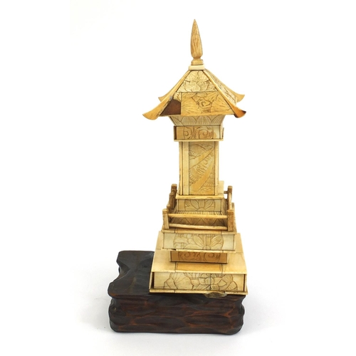 2357 - Oriental ivory pagoda opening to reveal a miniature Buddha, raised on a hardwood base, 26cm high