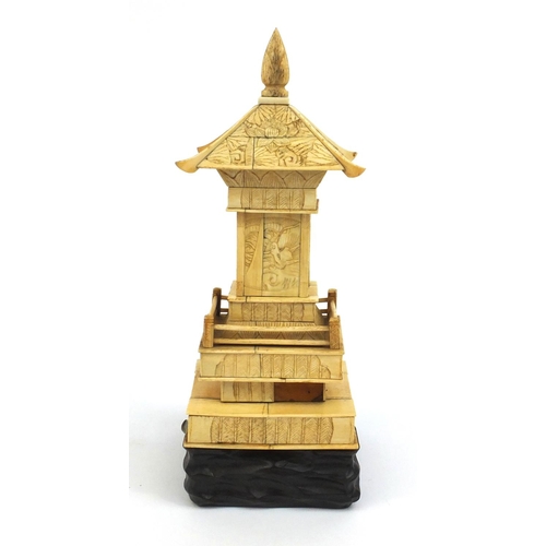 2357 - Oriental ivory pagoda opening to reveal a miniature Buddha, raised on a hardwood base, 26cm high