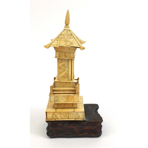 2357 - Oriental ivory pagoda opening to reveal a miniature Buddha, raised on a hardwood base, 26cm high