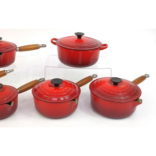 2315 - Group of Le Creuset red cast iron kitchenalia comprising graduated set of five lidded saucepans and ... 