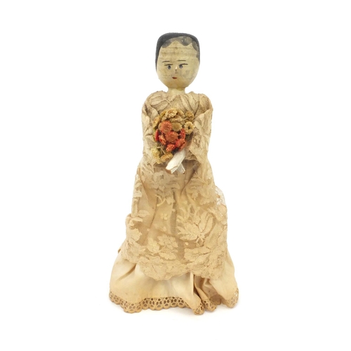 2292 - Antique hand painted wooden doll dressed in a silk costume holding a bunch of flowers, 31cm high