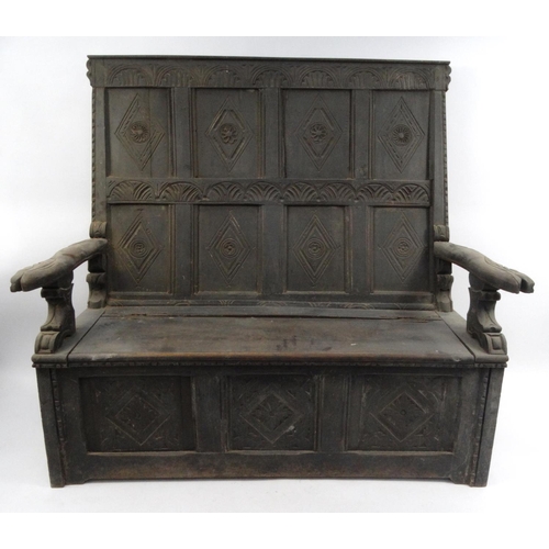 31 - Antique oak panelled settle with carved decoration and lift up seat, 142cm high x 152cm wide x 66cm ... 