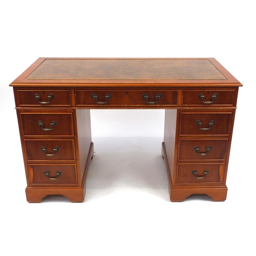 2022 - Yew twin pedestal desk with tooled leather top above an arrangement of nine drawers, 76cm high x 122... 