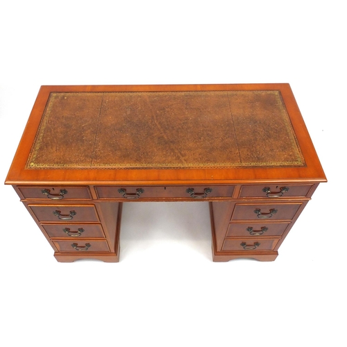 2022 - Yew twin pedestal desk with tooled leather top above an arrangement of nine drawers, 76cm high x 122... 