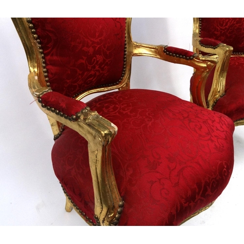 25 - Pair of carved gilt wood elbow chairs with red upholstered backs and seats