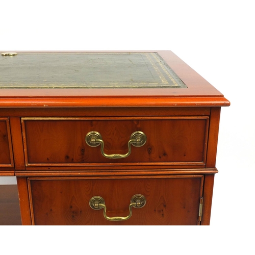 69 - Yew wood desk with tooled leather top, fitted with two drawers above a cupboard door and slide out s... 