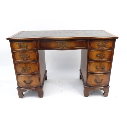 7 - Reproduction mahogany desk with tooled leather top above an arrangement of nine bow fronted drawers,... 