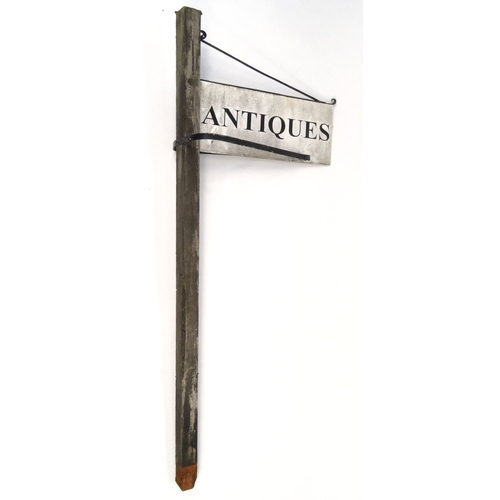 109 - An antique's shop sign on wooden post, the sign 67cm x 30cm