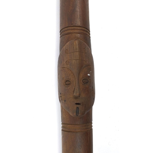 328 - African hardwood ceremonial spear carved in relief with face masks, 208cm long