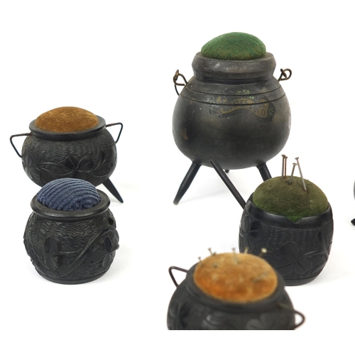 7 - Collection of Irish Bog oak pin cushions, mostly in the form of cauldrons some decorated with shamro... 