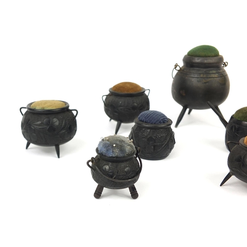 7 - Collection of Irish Bog oak pin cushions, mostly in the form of cauldrons some decorated with shamro... 
