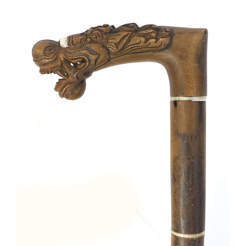 39 - Oriental hardwood segmented walking stick with carved handle in the form of a dragons head, 90cm lon... 