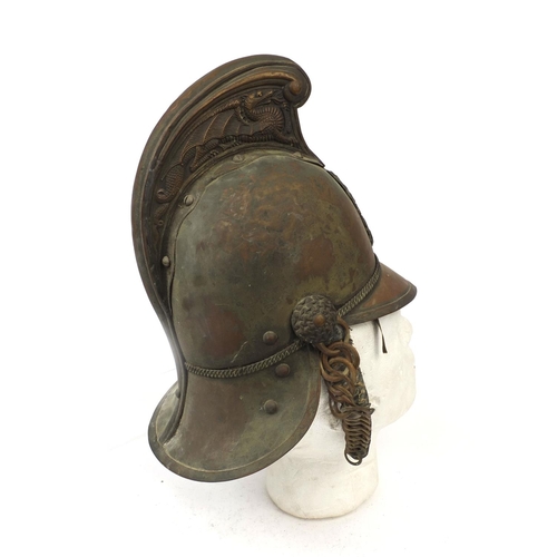 122 - Plated copper Fireman's helmet with applied crest and chin strap, the high comb with dragon decorati... 