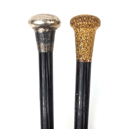 33 - Two ebonised walking sticks one with gold plated pommel the other with a silver pommel, the longest ... 