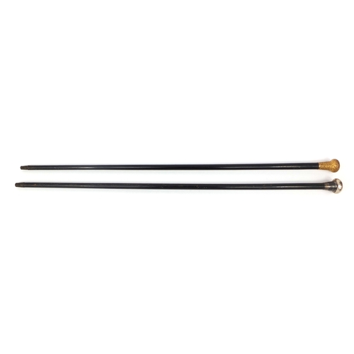 33 - Two ebonised walking sticks one with gold plated pommel the other with a silver pommel, the longest ... 