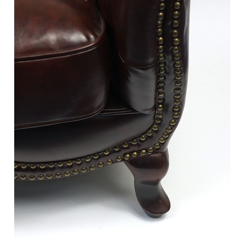 2009A - Pair of brown leather club chairs with horse shoe shaped back and button upholstery, 79cm high