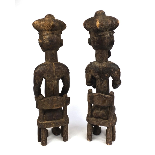 509 - Pair of African carved wooden figures, both seated, one of a male the other of a female, the tallest... 