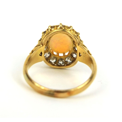 777 - Unmarked gold opal and diamond ring set with an oval cabochon opal surrounded by fourteen diamonds, ... 