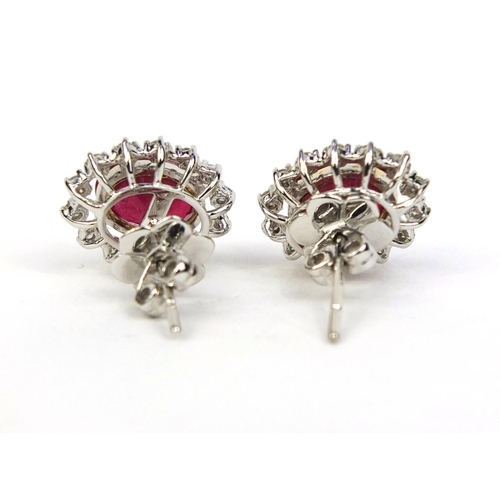 780 - Pair of 18ct white gold ruby and diamond earrings, each set with a single ruby and fourteen diamonds... 