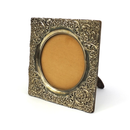 669 - Square silver easel photo frame, profusely embossed with floral decoration, H M Birmingham 1900, 19c... 