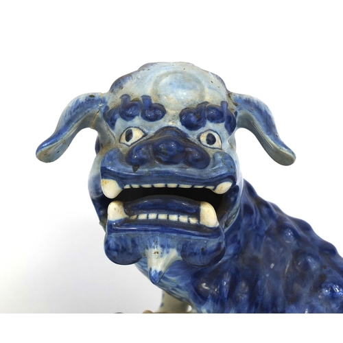 562 - Pair of delft blue and white pottery foo dogs, both raised on pierced floral bases, each 24cm high