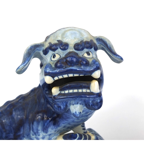 562 - Pair of delft blue and white pottery foo dogs, both raised on pierced floral bases, each 24cm high