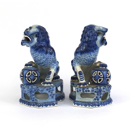 562 - Pair of delft blue and white pottery foo dogs, both raised on pierced floral bases, each 24cm high