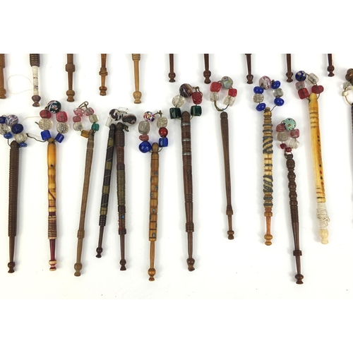 42 - Collection of sewing interest wooden and bone bobbins, mostly with glass beads, the largest approxim... 