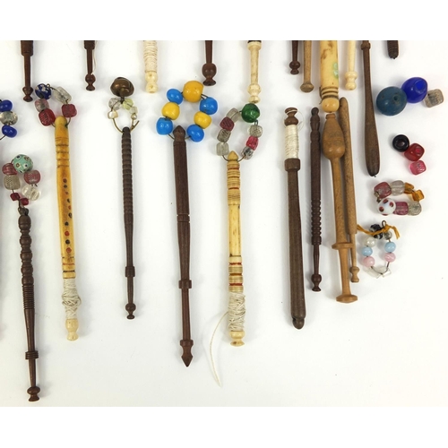 42 - Collection of sewing interest wooden and bone bobbins, mostly with glass beads, the largest approxim... 