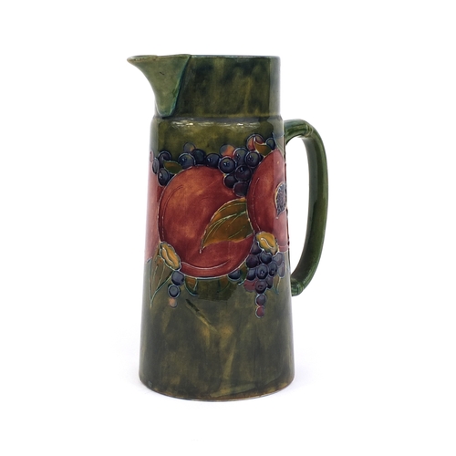 622 - William Moorcroft pomegranate pattern pottery jug of tapering form, with hand painted and tube lined... 