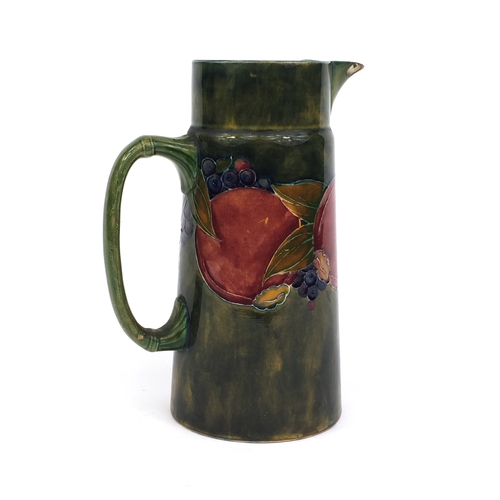 622 - William Moorcroft pomegranate pattern pottery jug of tapering form, with hand painted and tube lined... 