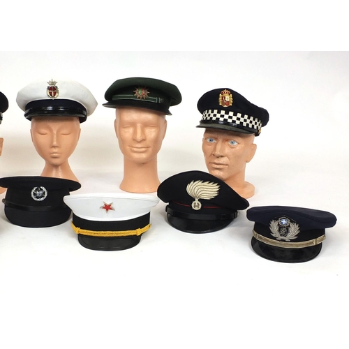 349 - Group of twelve police and fire caps, various countries some with badges, some with labels to the in... 