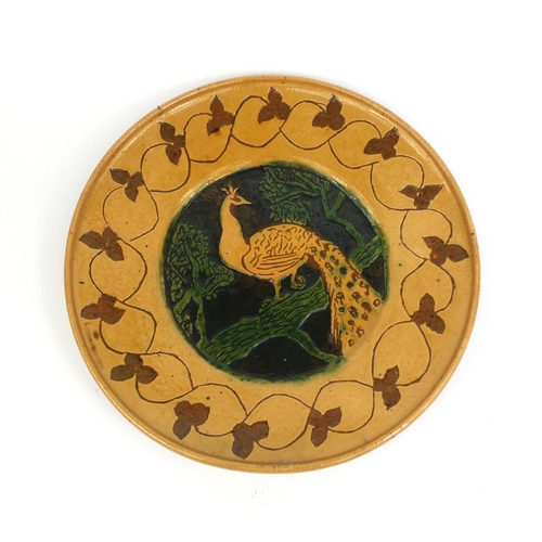 565 - Large pottery charger hand painted with a stylised peacock on a branch within a floral boarder, 37.5... 