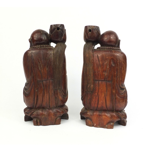 477 - Pair of Chinese root carved lamp bases, each of a Buddha holding a nut, each 37cm high