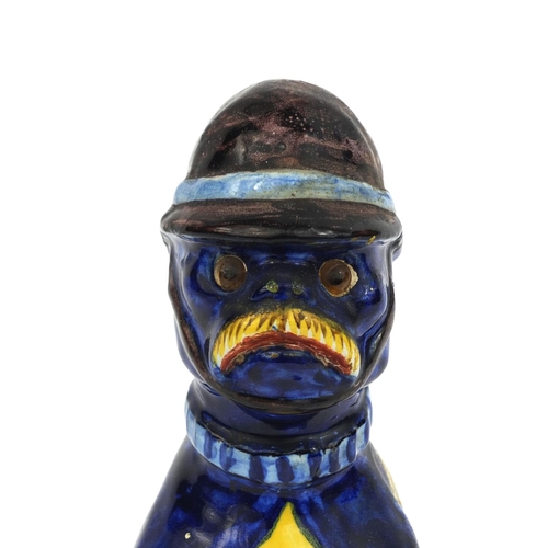 616 - Mosanic faience glazed pottery cat seated wearing a policeman's helmet, hand painted with hearts and... 