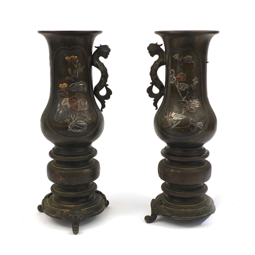 472 - Pair of Japanese bronze twin handled vases, with animalia handles, each decorated in silver with fig... 