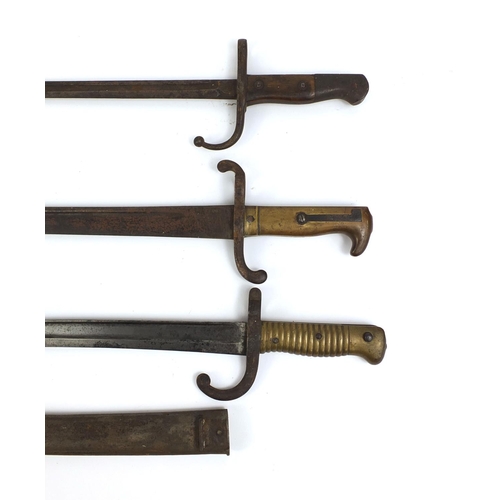 308 - Group of three Military interest bayonets including one with scabbard and one with wooden grip, each... 