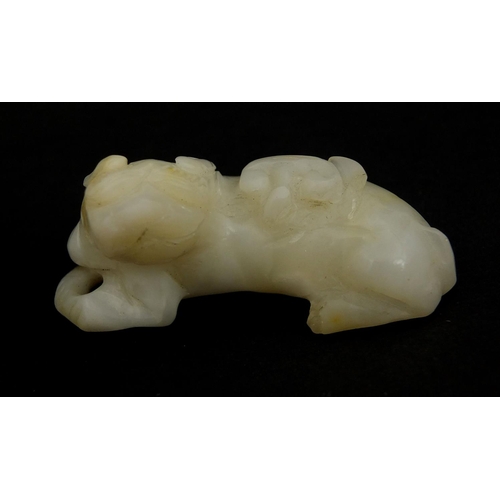 439 - Two Chinese pale jade carvings comprising one of a buffalo biting a branch and one of a dog a foo re... 