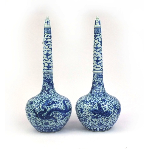 384 - Pair of Chinese blue and white porcelain long neck bottle vases with stoppers, one profusely hand pa... 