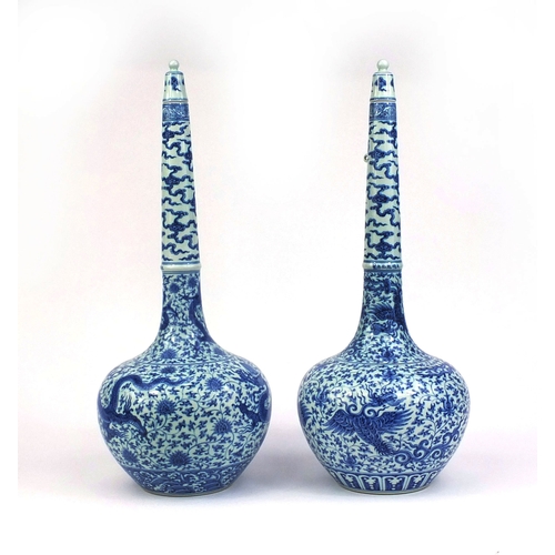 384 - Pair of Chinese blue and white porcelain long neck bottle vases with stoppers, one profusely hand pa... 