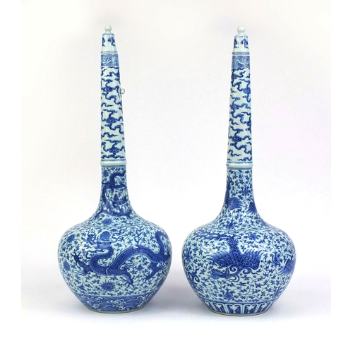 384 - Pair of Chinese blue and white porcelain long neck bottle vases with stoppers, one profusely hand pa... 