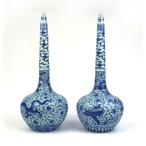 384 - Pair of Chinese blue and white porcelain long neck bottle vases with stoppers, one profusely hand pa... 