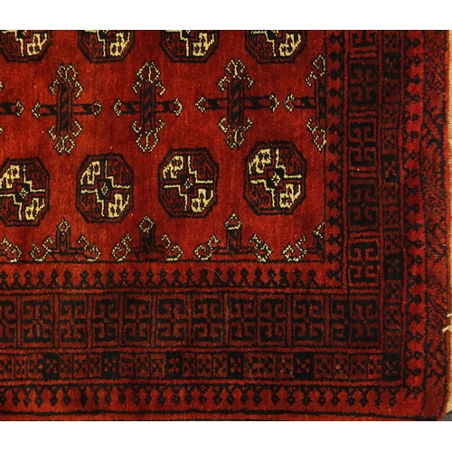 2034 - Rectangular Afghan rug, having a repeat tribal gul design, within geometric boarders onto a red grou... 