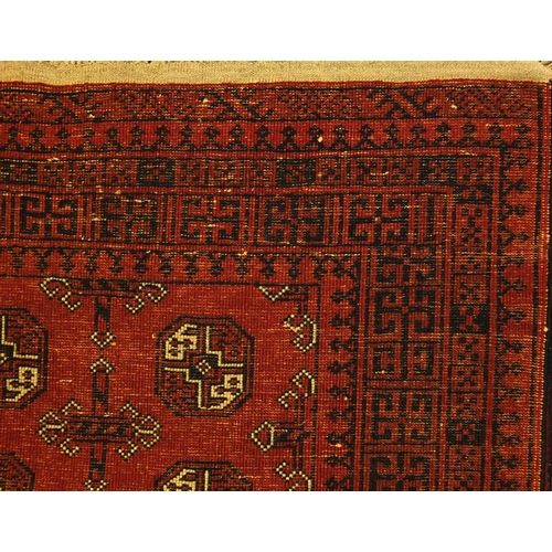 2034 - Rectangular Afghan rug, having a repeat tribal gul design, within geometric boarders onto a red grou... 